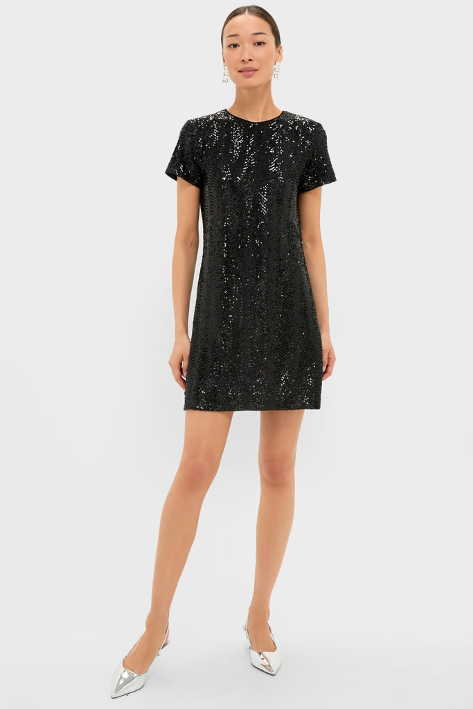 Woman models the Black Sequin Roya Swing Mini Dress, a classic and effortless above-the-knee style, paired with pointed silver slingback heels and crystal-style earrings.