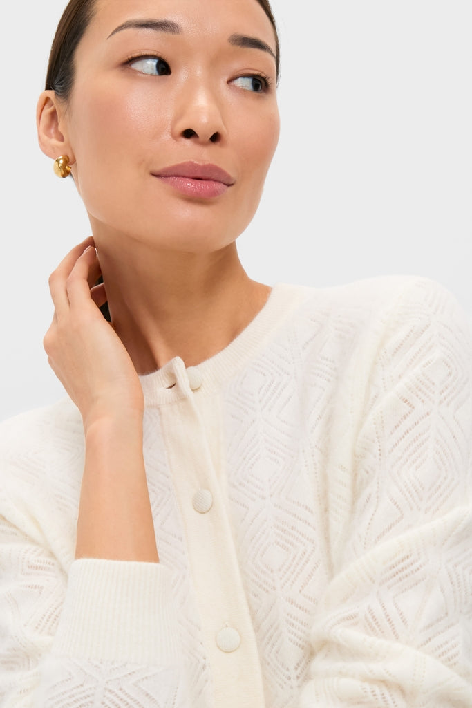 Woman wearing the Ivory Brushed Merino Wool Macy Cardigan, featuring a classic diamond-pattern texture and button-front design; accessorized with a chunky gold hoop earring for an effortless, high-end look.