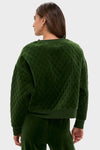 Woman in a classic, forest-green Douglas Fir Velour Bennett Pullover, showcasing its quilted body, relaxed fit, and ribbed finishes, paired with matching velour pants.