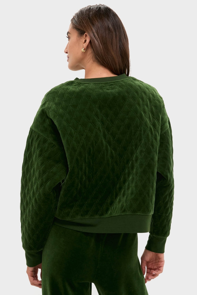 Woman in a classic, forest-green Douglas Fir Velour Bennett Pullover, showcasing its quilted body, relaxed fit, and ribbed finishes, paired with matching velour pants.
