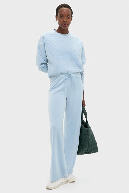 Young woman in Blue Fog Velour Bennett Pullover, showcasing its classic quilted design, relaxed fit, and high-end feel, paired effortlessly with matching pants for a fun, chic look.