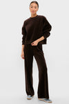 Woman models the Chocolate Brown Velour Bennett Pullover with matching pants, exuding an effortless, high-end look, paired with casual sneakers for a fun, classic style.