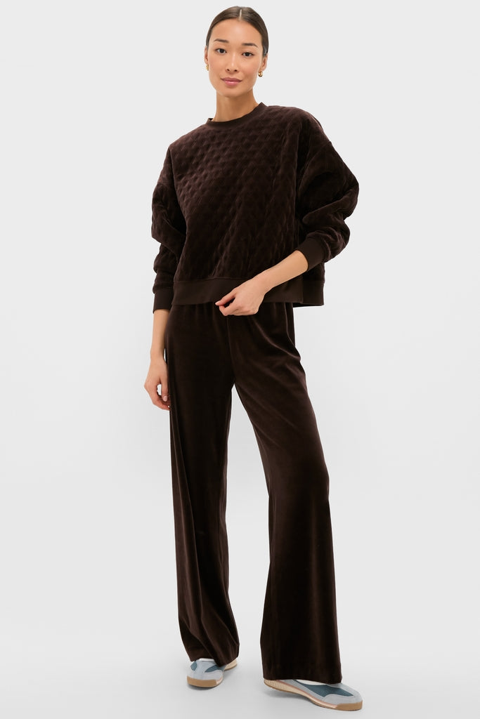 Woman models the Chocolate Brown Velour Bennett Pullover with matching pants, exuding an effortless, high-end look, paired with casual sneakers for a fun, classic style.