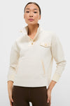 Young adult models the classic Cream Snap Neck Brooke Pullover, featuring an effortless high-end design with a textured finish, snap collar, and convenient pocket detail.