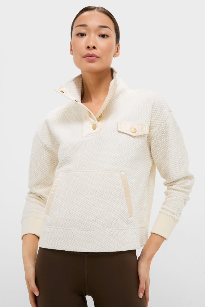 Young adult models the classic Cream Snap Neck Brooke Pullover, featuring an effortless high-end design with a textured finish, snap collar, and convenient pocket detail.