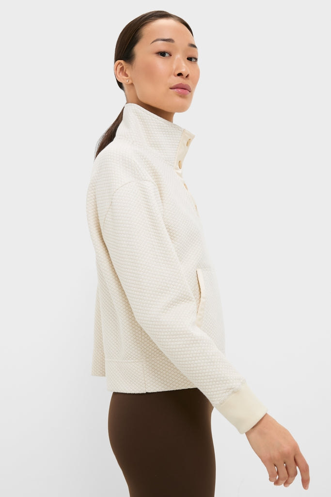 Model in profile wearing the classic Cream Snap Neck Brooke Pullover, featuring a high snap-button collar, paired with dark brown leggings for an effortless, high-end look.