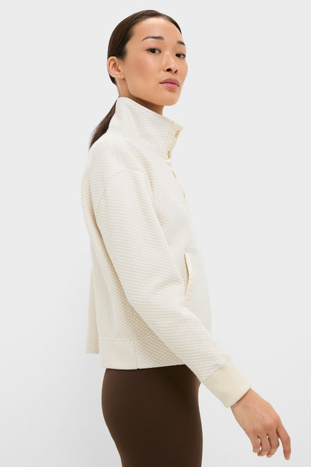 Model in profile wearing the classic Cream Snap Neck Brooke Pullover, featuring a high snap-button collar, paired with dark brown leggings for an effortless, high-end look.