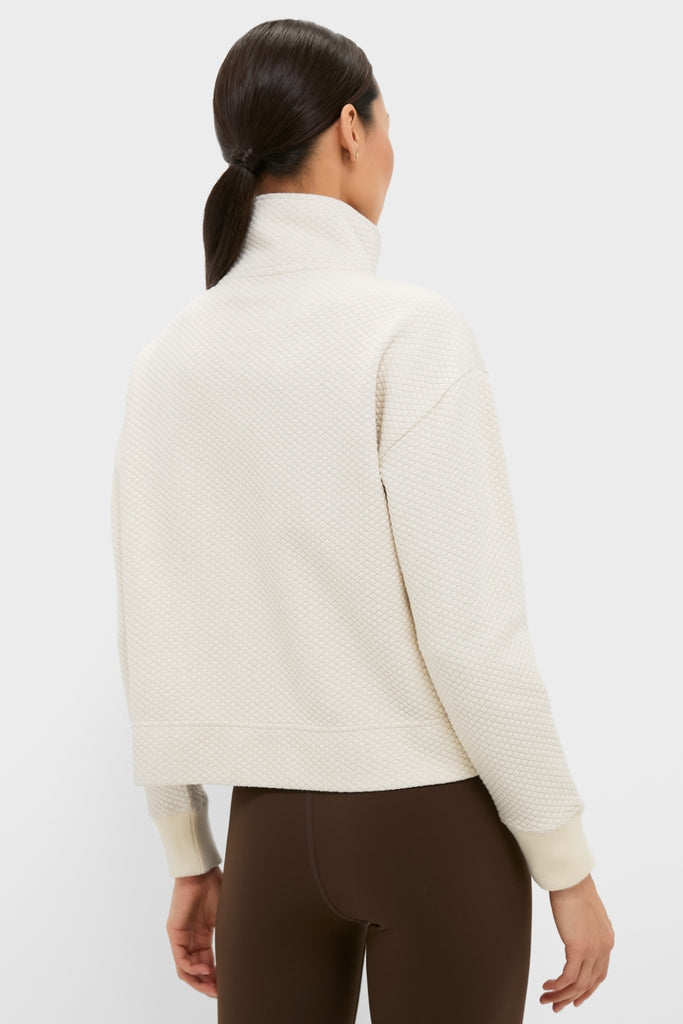 Back view of a model in a classic, cream Snap Neck Brooke Pullover with a high collar and ribbed cuffs, paired with brown leggings for an effortless, high-end look.