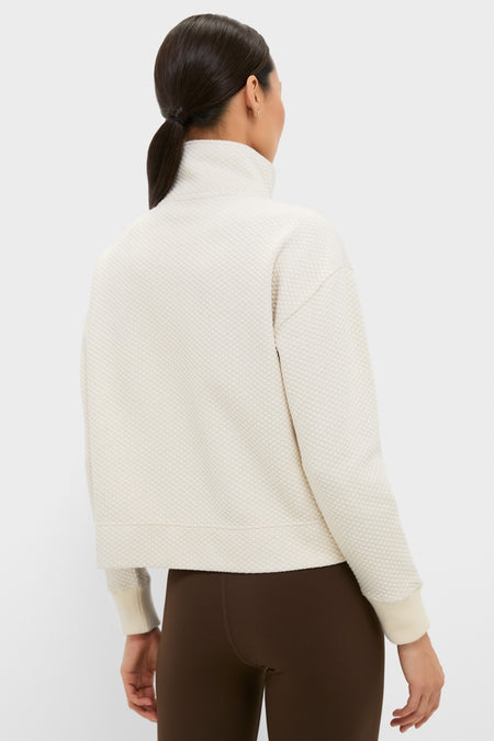 Back view of a model in a classic, cream Snap Neck Brooke Pullover with a high collar and ribbed cuffs, paired with brown leggings for an effortless, high-end look.