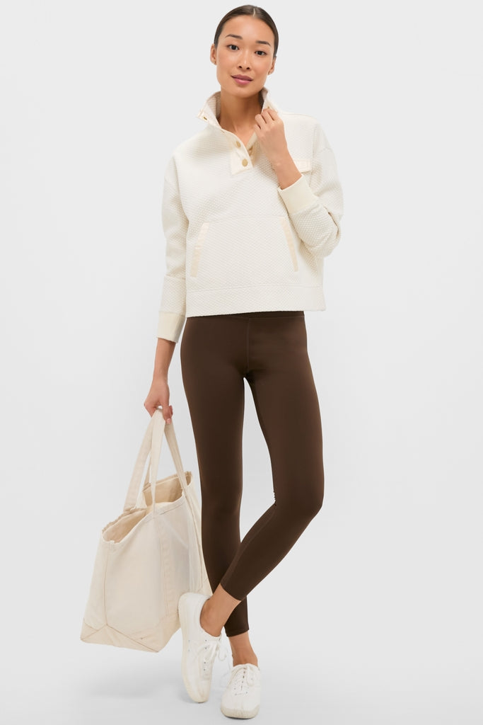 Woman wearing the classic Cream Snap Neck Brooke Pullover, exuding effortless style with its quilted texture, paired with chocolate leggings and a canvas tote for a fun, high-end look.