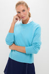 Young woman in a classic Bright Blue Washable Cashmere Malcolm Crewneck over a white shirt, showcasing an effortless, high-end style with subtle scalloped-stitch navy skirt.