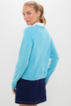 Young woman wearing the classic, high-end Bright Blue Washable Cashmere Malcolm Crewneck with rib-knit trim and a navy skirt, exuding an effortless and fun style.