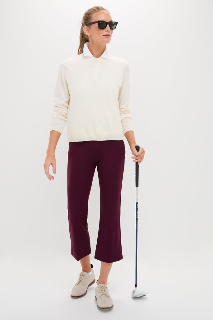 Person wearing the Buttercream Washable Cashmere Malcolm Crewneck with embroidered details, exuding classic and effortless style, holding a golf club, embodying high-end, fun fashion.