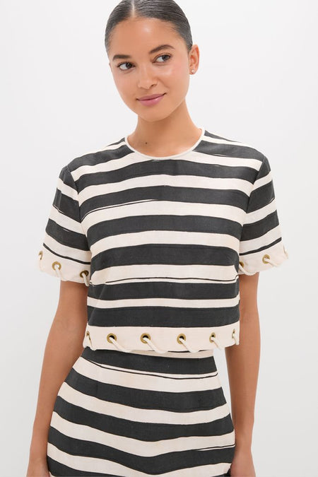 Woman in a classic Black Stripe Story Top, featuring effortless style with short sleeves and grommet detailing, embodying high-end fashion with a fun, confident twist.