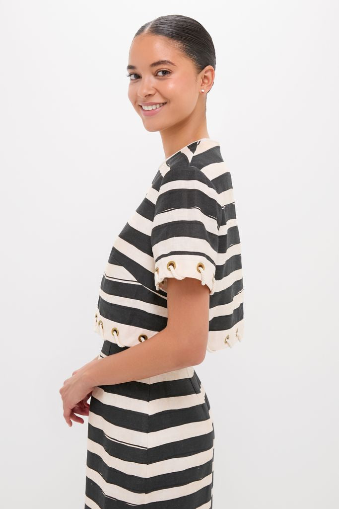 Young woman in profile wearing the Black Stripe Story Top, showcasing classic, effortless style with bold stripes and grommet details, embodying Tuckernuck's fun, high-end fashion.
