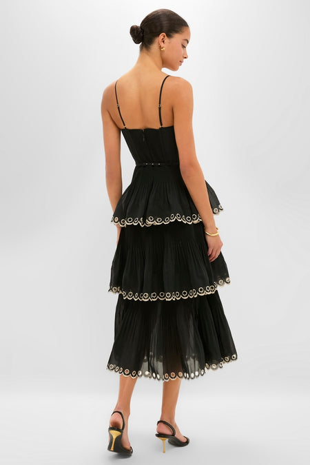 Woman wearing a classic Black Embroidered Tiered Midi Dress with scalloped trim, adjustable straps, and stiletto heels, exuding effortless high-end style and fun sophistication.