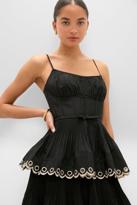 Model in a classic, high-end Black Embroidered Tiered Midi Dress with a corset bodice, scalloped trim, and pleated skirt, embodying effortless and fun elegance.