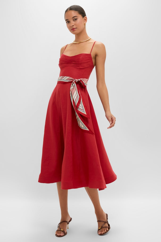 Model in Red Rebellion Tuck Midi Dress, a classic, high-end A-line linen dress with effortless ruching, paired with fun accessories like a striped belt and gold jewelry.