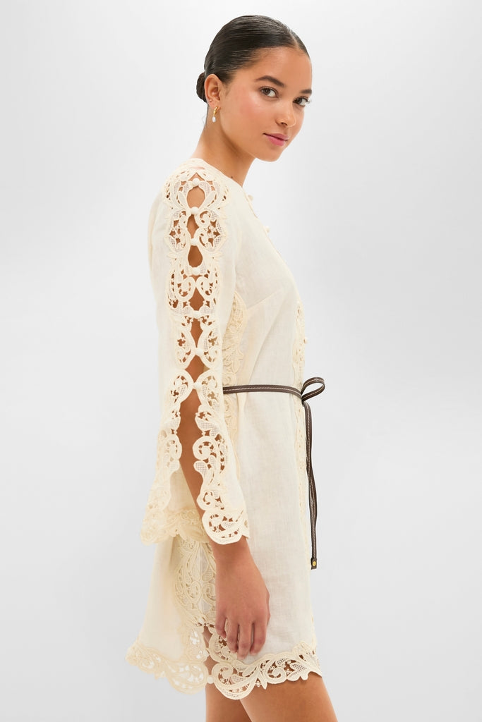 Young woman models the classic Cream Awaken Embroidered Tunic, featuring intricate lace cut-outs, a cinched waist, and keyhole bust, exuding effortless, high-end charm.