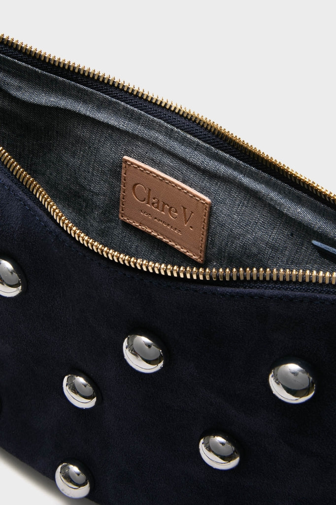 Navy Suede Lune Bag: A classic, high-end suede pouch with polished silver dome studs, featuring an effortless gold-tone zipper and a fun, gray-lined interior with Clare V. branding.