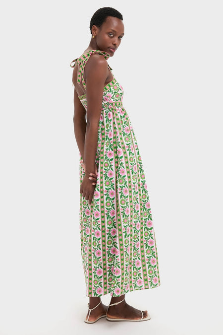 Emerald Border Mykonos Dress: A classic, sleeveless sundress with floral print and bow-tied straps, paired with effortless white-strap sandals, embodying a fun, high-end style.