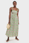 Emerald Border Mykonos Dress: A classic, effortless sundress with pink floral motifs, wide straps, and a gathered skirt, paired with a woven straw tote and strappy sandals.
