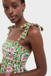 Woman wearing the Emerald Border Mykonos Dress, featuring classic, effortless embroidery of green vines and pink flowers, with bows on shoulder straps, exuding a fun, high-end style.