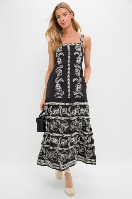 Model in Sweetheart Rio Dress, a classic black sundress with floral embroidery, paired with a black wicker handbag and espadrille wedges for an effortless, high-end look.