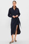 Woman models the classic Midnight Alessandra Sarong Shirt Dress, featuring a side wrap and mid-calf drape, accessorized with a chunky gold necklace for an effortless, high-end style.
