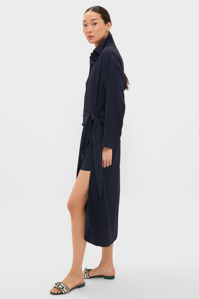 Young woman in a classic, high-end Midnight Alessandra Sarong Shirt Dress with effortless style, featuring a self-tie belt and high side slit, paired with fun slip-on sandals.