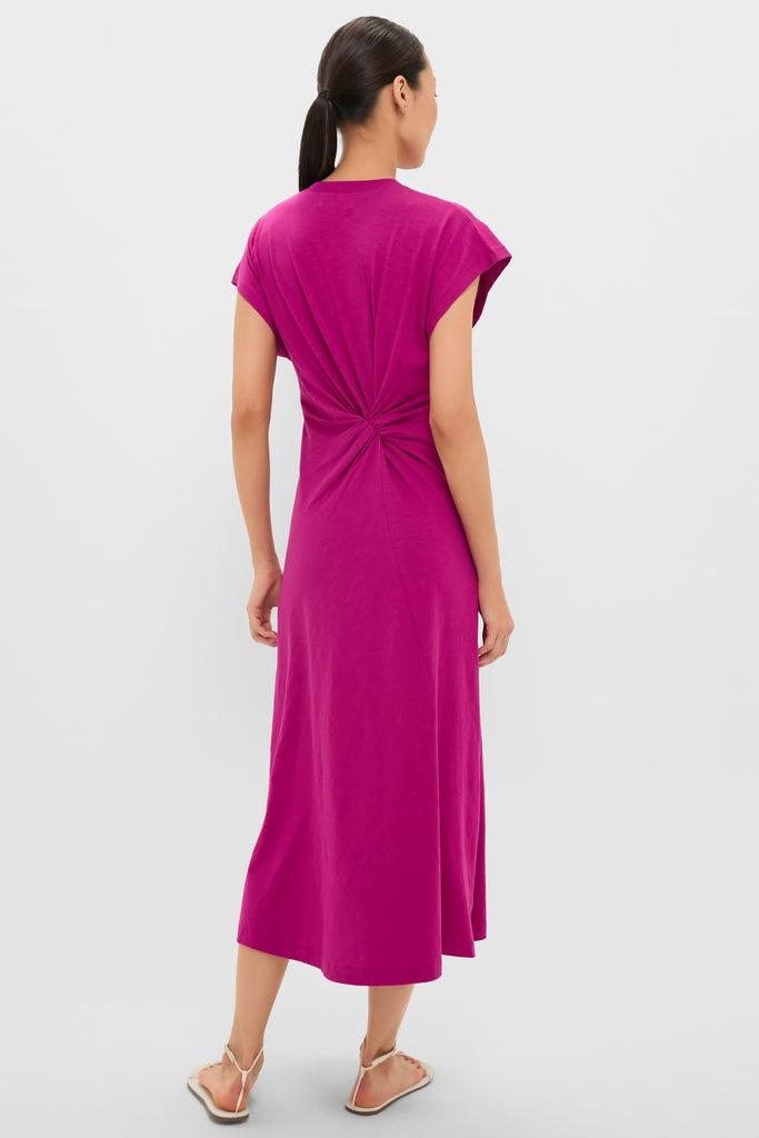 Woman wearing the Fuchsia Volta Twist Dress, featuring a classic gathered twist detail and cap sleeves, paired with white strappy sandals for an effortless, high-end look.