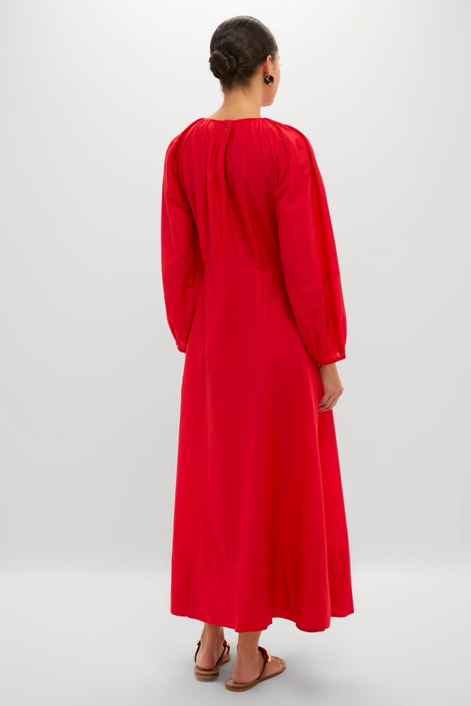 Woman in a classic, bright red Tigerlily Bonita Dress with long sleeves, effortlessly styled with a neat bun and flat sandals, embodying high-end, fun fashion.