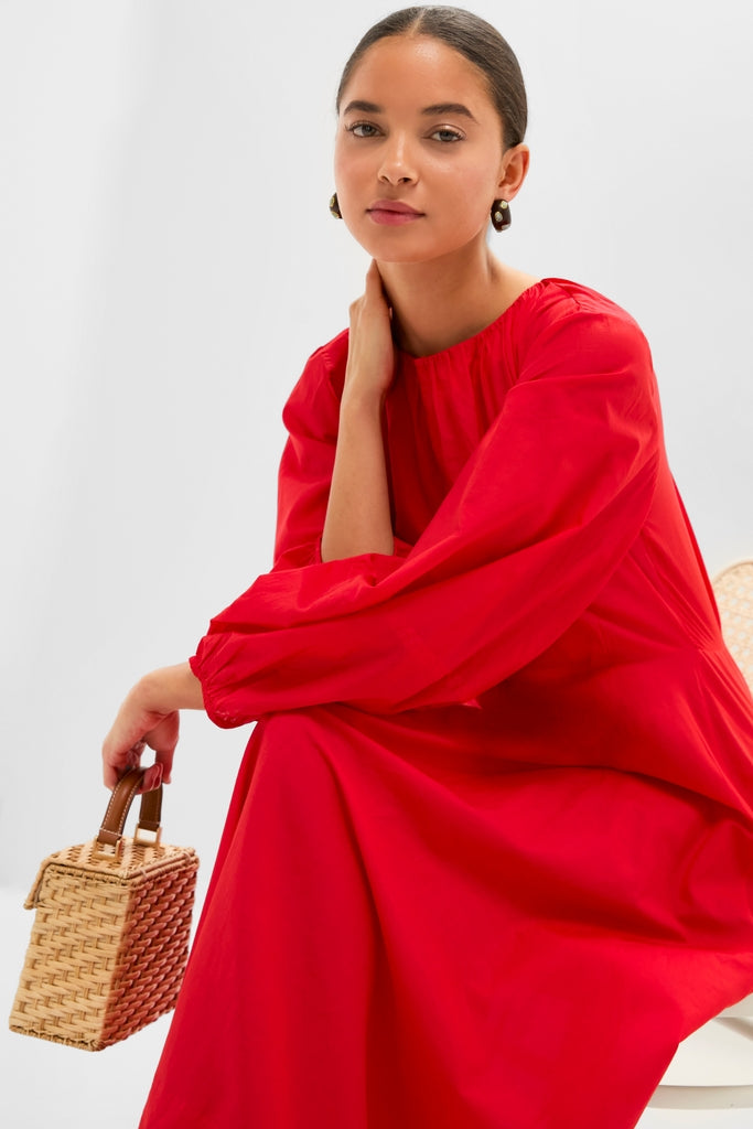 Model in a classic Tigerlily Bonita Dress with balloon sleeves, paired effortlessly with a high-end woven wicker handbag, exuding a fun and confident style.