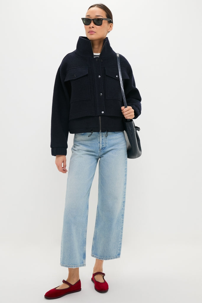 Woman wearing the Midnight Selva Cropped Bomber, a classic wool-style jacket with snap buttons and flap pockets, paired with wide-leg jeans and red flats for an effortless, high-end look.