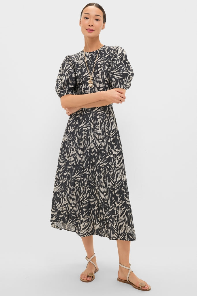 Model wearing the Abstract Animal Midnight Bettina Maxi, a classic black midi dress with an effortless abstract print, puffed sleeves, and a fitted waist, paired with a gold necklace.