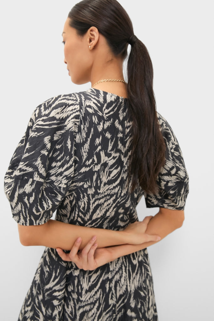 Woman wearing the Abstract Animal Midnight Bettina Maxi, a classic, high-end dress with a brushstroke pattern, showcasing an effortless, fun style with puffed sleeves, arms crossed behind.