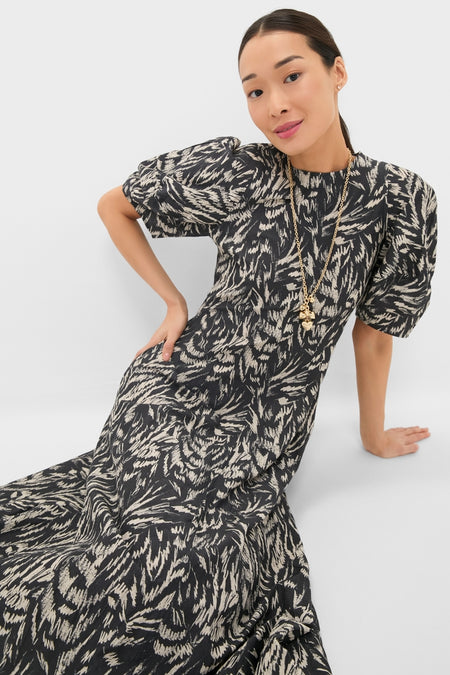 Woman in a classic Abstract Animal Midnight Bettina Maxi dress with puffed sleeves, layered gold necklaces, embodying effortless elegance and fun, high-end style.