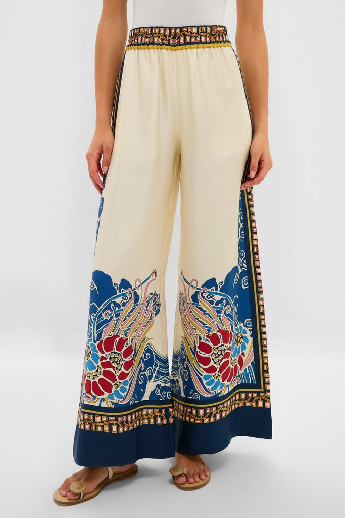 Model showcasing Lemuria Placee Palazzo Pants in a creamy beige with a vibrant floral hem. These high-waisted, wide-leg trousers offer a classic, effortless, and high-end style.
