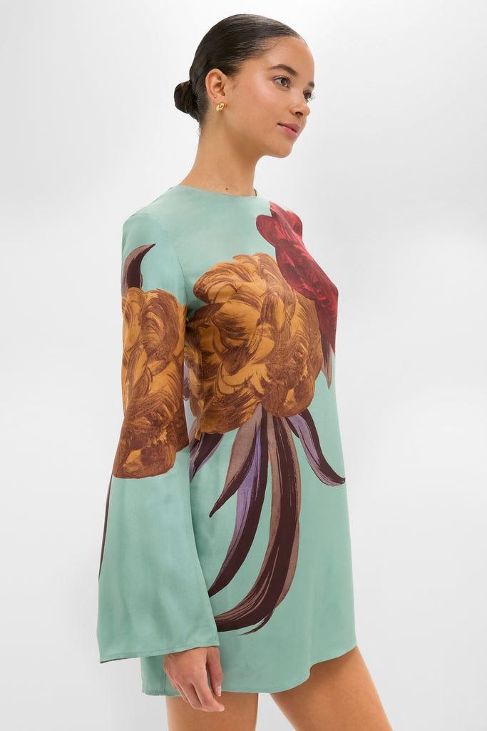 Woman in profile wearing the Peony Placee Mini Supremes Swing Dress with painterly blooms, bell sleeves, and sleek bun; a classic, high-end, effortless party choice.