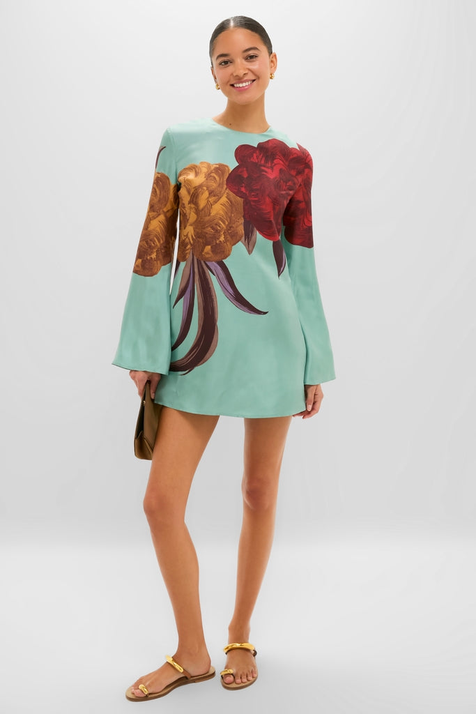 Model wears the classic Peony Placee Mini Supremes Swing Dress with botanical motifs, bell sleeves, and gold sandals, embodying effortless, high-end style for fun occasions.