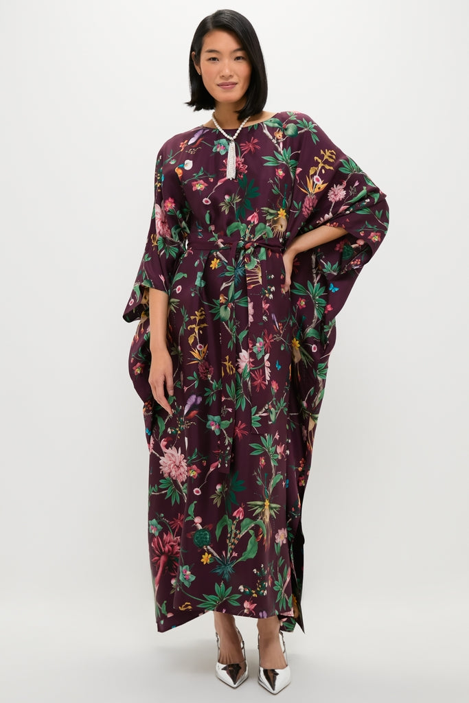 Woman wearing the Zooflora Square Kaftan, a classic, high-end, burgundy floral silk dress with kimono sleeves and an effortless, fun style, accessorized with a beaded tassel necklace.