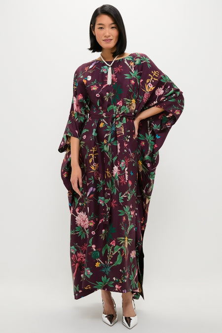 Woman wearing the Zooflora Square Kaftan, a classic, high-end, burgundy floral silk dress with kimono sleeves and an effortless, fun style, accessorized with a beaded tassel necklace.