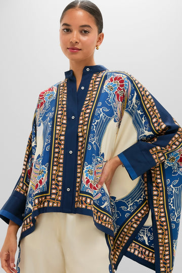 Young woman in a classic Lemuria Placee Foulard Shirt, showcasing an effortless, high-end look with a bold print and cape-style cut, styled with light trousers.