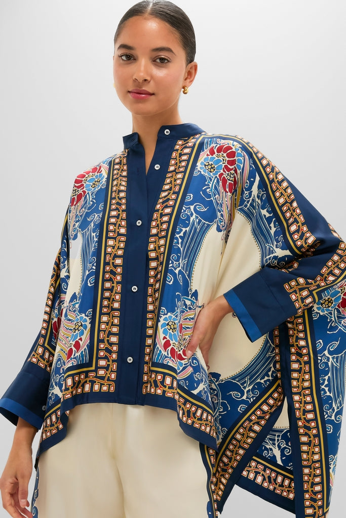 Young woman in a classic Lemuria Placee Foulard Shirt, showcasing an effortless, high-end look with a bold print and cape-style cut, styled with light trousers.