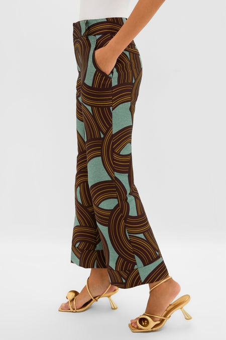 Person models Montecarlo Jacquard Hendrix Pants with an abstract swirl pattern, paired with metallic gold open-toe sandals, embodying a classic, effortless, and high-end style.