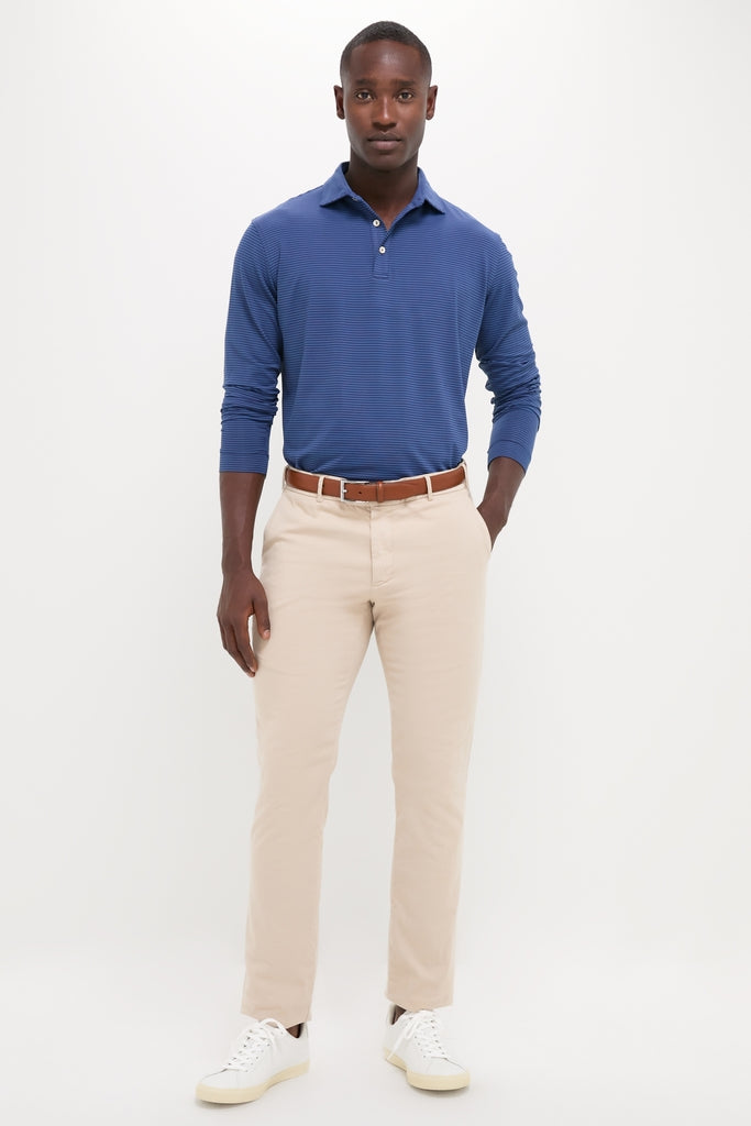 Male model in a classic, effortless outfit featuring the Navy Lyons Performance Jersey Long Sleeve Polo, tucked into khaki chinos with white sneakers, embodying high-end casual-smart style.