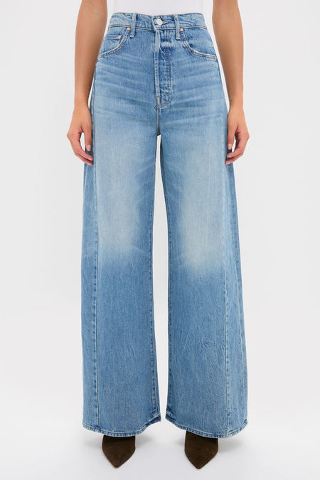 Person wearing Folk Star The Pipe-Dream Button Sneak jeans, showcasing classic, effortless high-waisted denim with ultra-wide legs and dark, pointed-toe boots for a fun, high-end look.