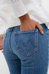Close-up of a person wearing the Hokey Pokey The Outsider Sneak jeans, featuring classic mid-rise bootcut style with an M stitch on the back pocket, effortlessly chic.