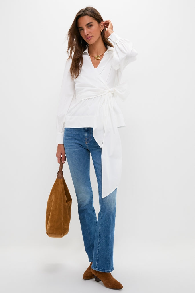 Woman in classic Hokey Pokey The Outsider Sneak jeans, effortlessly styled with a white wrap blouse and brown suede accessories for a fun, high-end look.