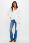 Woman wearing Hokey Pokey The Outsider Sneak jeans, a classic mid-rise bootcut style paired with an effortless white wrap blouse and brown suede ankle boots.